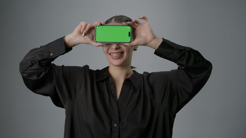 A smiling model with a smartphone on a white background. Advertising on chromakey