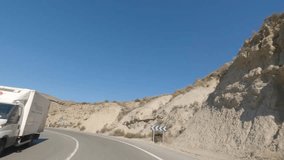 First person view, FPV, from dashcam of car driving in the Tabernas desert in Almeria, Andalusia, Spain. Road trip video in POV, with bright, sunny, clear sky