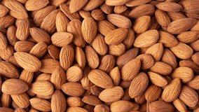 Almond top view 4K video. Almonds top view background. Whole almond nuts flat lay.