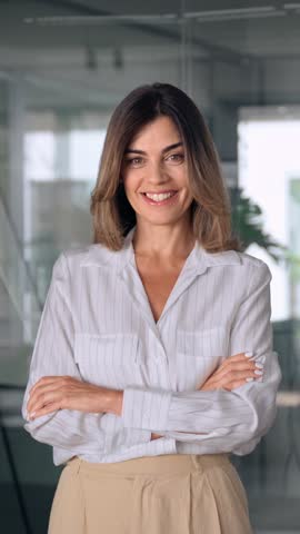 Beautiful hispanic senior business woman with crossed arms smiling at camera. European or latin confident mature good looking middle age leader female businesswoman on office background, vertical. Royalty-Free Stock Footage #3446631107
