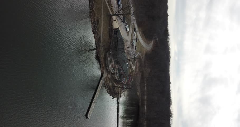 4k high resolution panning aerial drone video of water at a lake and bare trees close to the shoreline.