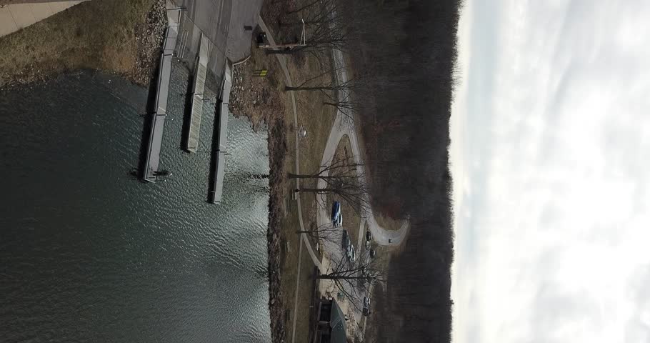 4k high resolution panning aerial drone video of water at a lake and bare trees close to the shoreline.