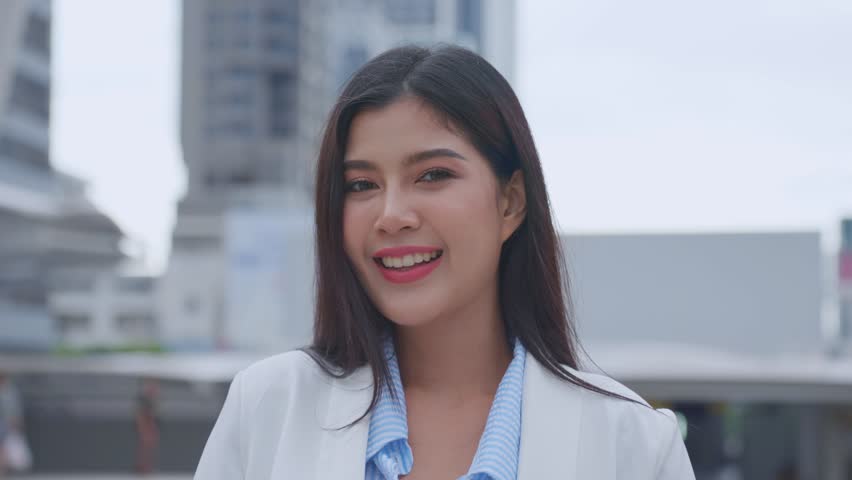 Portrait of Asian youg beautiful businesswoman standing outdoor in city. Attractive employee girl worker feel happy and confident then smile, looking at camera. Job application and recruitment concept