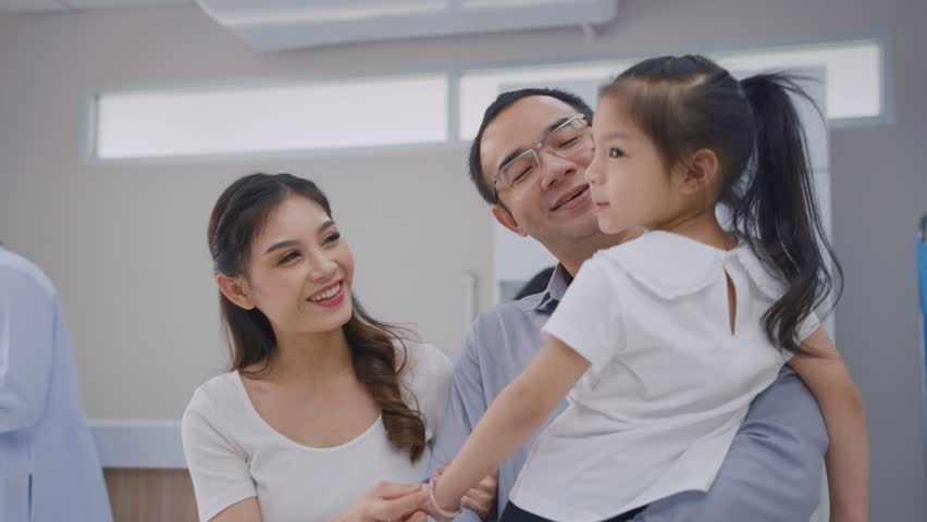Asian family patient walking through corridor in the hospital ward. Attractive couple and daughter standing in hallway waiting on line que to receive medicine in pharmacy counter at medical center.
