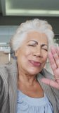 Vertical shot of a senior biracial woman having a video call, blowing a kiss to the camera. Seniors and technology concept.