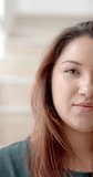 Vertical video half portrait of plus size biracial woman smiling at home, slow motion. Wellbeing, domestic life and healthy lifestyle, unaltered.