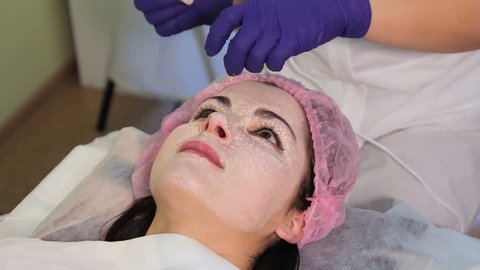 The procedure of lightening the skin. The girl beautician explain anything. The patient's face in close-up.