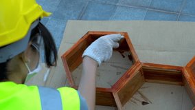 Asian female worker painting wooden furniture at a job site.
