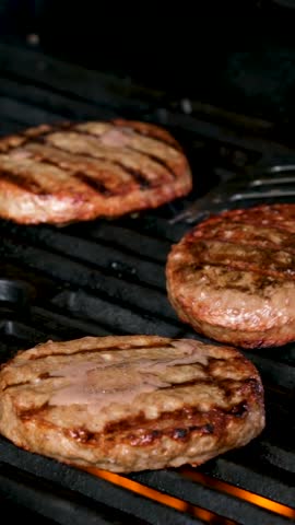 Cooking burgers on a hot grill with a flame Beef cutlets cooked on a barbecue grill.Cooking beef and pork patty for party.
