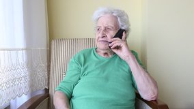 woman, A lovely senior old woman talking on phone in living room at home. video of senior people