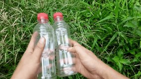 Two used plastic bottles are held by a man outside