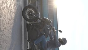 Caucasian man rides on an electric motorcycle. Vertical video. 
