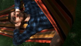 Man sleeping in hammock outdoors. Carefree man relaxing in hammock on sunny summer day. Vertical video - Powered by Shutterstock - Get 15% off with code: PIKWIZARD15