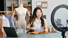 Fashion blogger concept, Young Asian women selling clothes on video streaming.Startup small business SME, using smartphone or tablet taking receive and checking
