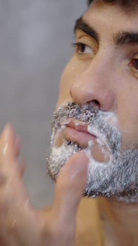 Handsome guy shaving with a razor at home