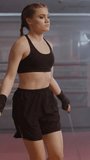 Woman fighter trains and jumping rope, coordination training, kickboxing training day in the boxing gym, strength fit body, vertical video.