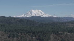 Ungraded aerial drone footage of Mount Rainier under light blue sky on a sunny winter day in Washington State.