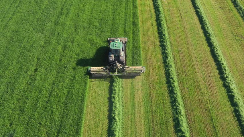 Modern agricultural tractor on autopilot mows fresh green grass to hay in straight lines. Computer with lidar radar helps to increase rural productivity and reduce CO2 emissions and pollution Royalty-Free Stock Footage #3447013985