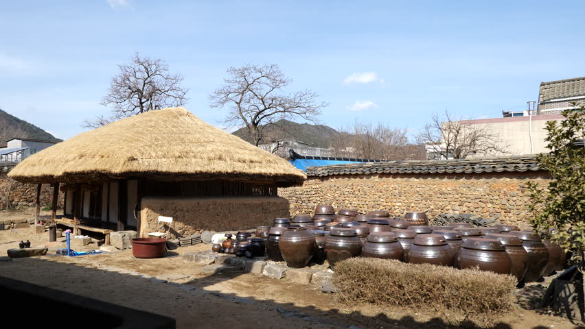 Jangdokdae next to the thatched roof of a traditional Korean house