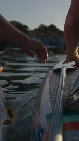 Caucasian couple hold hands as they watch the sunset in the water