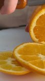 Woman slicing orange in kitchen close up. Young asian housewife slicing raw orange to prepare for food and dinner. Home cooking concept. High quality 4k footage
