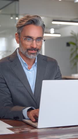 Serious mature European business man ceo trader using computer, typing, working in modern office, doing online data market analysis, thinking planning tech strategy looking at laptop, vertical. Royalty-Free Stock Footage #3447070343