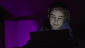 Child Using Digital Tablet Evening at Home. Teen Girl Watching Online Video Social Media on Digital Tablet in Bed in Bedroom at Night. Dependence on Social Networks in Children. Not Healthy Sleep.