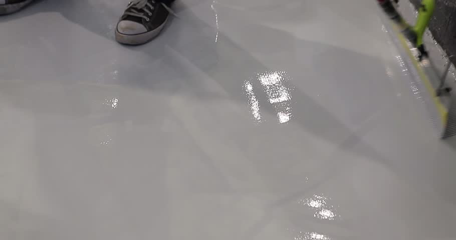 A builder distributes resin flooring material evenly using a Scraper Float. A builder is applying polymer floors using Scraper Float. The process of creating polymer floors