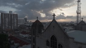Aerial video of birds and crows flying to a cross at a church in George Town, Penang, Malaysia, in the early morning