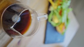 A glass teapot with coffee and a sandwich, close-up of a Man's hand taking a sandwich, slow motion, vertical video. The dishes are set for the meal, and the drink complements the dish.