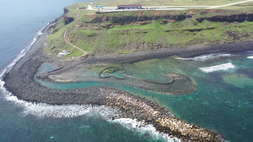 Aerial view of the beautiful Double-Heart of Stacked Stones or Twin-Heart Fish Trap, which is an old traditional fishing weir by the coastal cliffs of a cape, in Cimei Isalnd, Penghu, Taiwan Royalty-Free Stock Footage #3447254841