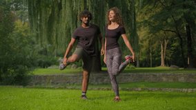 Active healthy couple Indian Arabian man and Caucasian woman athletes doing sport morning workout stretching body muscles warm-up exercises in park outdoors sporty people diverse male female training - Powered by Shutterstock - Get 15% off with code: PIKWIZARD15