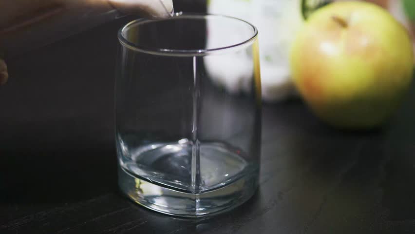 Pouring thick greek yoghurt oatmeal and apple smoothie into glass. Close up.