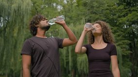 Healthy Indian man Caucasian woman drink in city park outdoor multiracial guy girl happy fitness couple sport people together relax pause break thirst drinking bottled water refresh wellness health - Powered by Shutterstock - Get 15% off with code: PIKWIZARD15