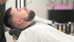 While trimming the beard, barber applies white powder to the face to soften the skin.
