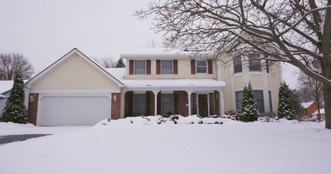 Yellow Colonial Home on Snowy Day. view of the exterior of a yellow suburban home during a snowy day