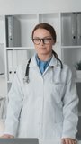 In this vertical video, a doctor in her office poses confidently for the camera, demonstrating professional elegance and self-confidence. Her posture reflects the strength and trust that she will