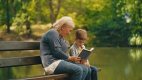 Happy granny reading fairytale to little grandson while resting on bench in park - Powered by Shutterstock - Get 15% off with code: PIKWIZARD15