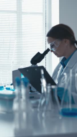 In this vertical video, a scientist in a biology lab focuses on conducting research on genetic modifications using cutting-edge technology. His attentive gaze and working attitude testify to his deep