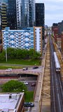 Following the skyway for subway train. Cars going by the road under the train railways. Cityscape of Chicago at backdrop. Vertical video.