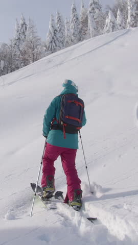 DRONE Fit Caucasian woman observes the beautiful snow covered nature while crossing the wintry landscape during ski touring trip to Bohinj. Active female tourist hikes along a hill while splitboarding Royalty-Free Stock Footage #3447439273