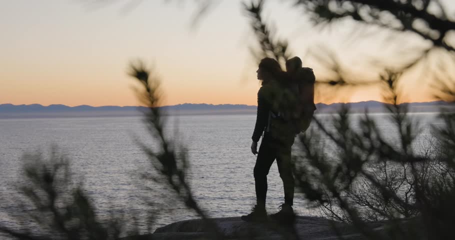 Mother and Baby Boy in backpack carrier hiking on Rocky ocean coast. Lighthouse park, West Vancouver, BC, Canada.