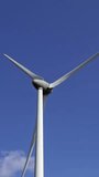 Windmill or wind turbine on wind farm in rotation to generate electricity energy. Vertical video