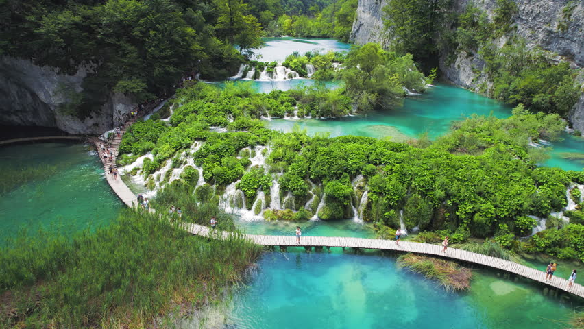 Hiking trail over crystal clear emerald water of lake. Path for tourists in mountain national park with waterfalls.