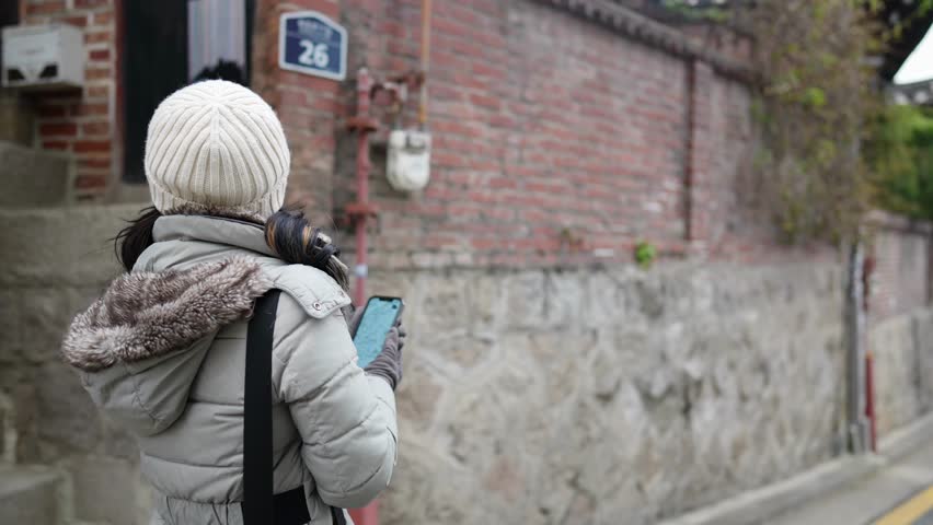 Slow-motion video of a young Filipino woman in her 20s taking a walk in Hanok Village, North Village, Seoul, Republic of Korea on a cold winter day