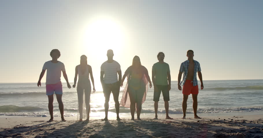 Diverse friends leap joyfully on a sunny beach. The group's exuberance captures the essence of carefree youth and friendship outdoors, slow motion. Royalty-Free Stock Footage #3447496251