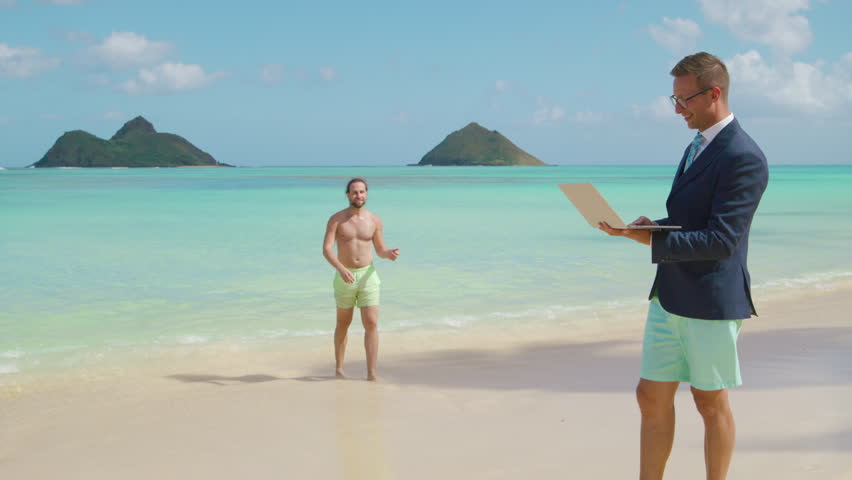 Two young male people on the stunning beach of the Hawaii island, one man working remotely on laptop and another gentleman with bare torso having fun. High quality 4k footage Royalty-Free Stock Footage #3447520729