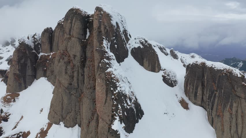 Snow-covered Ciucas Mountains peaks under overcast sky, aerial view
