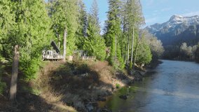 Log cabin in woods at sunny day. Forest cabin in magical Washington at forest river with mountain view. Small rustic countryside house hides between evergreen trees in mountain forest at blue river 4K - Powered by Shutterstock - Get 15% off with code: PIKWIZARD15