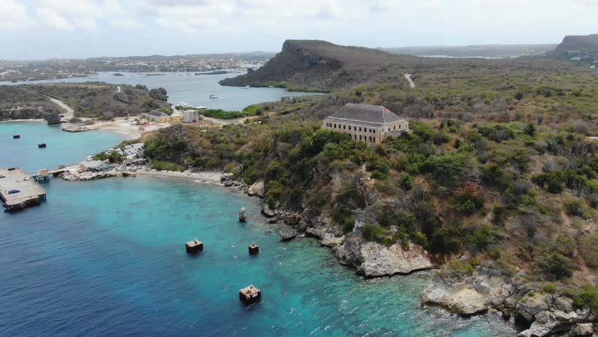 Tugboat beach in curacao with clear waters and rugged coastline, aerial view